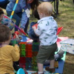 Toddlers at an outdoor event playing with magnet blocks and building toys.